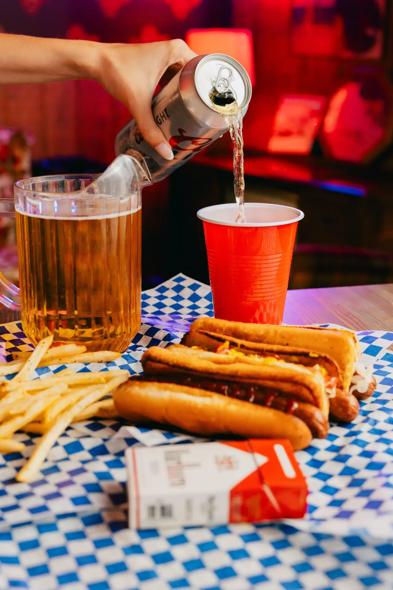 A draft beer and hot dogs on checkered paper